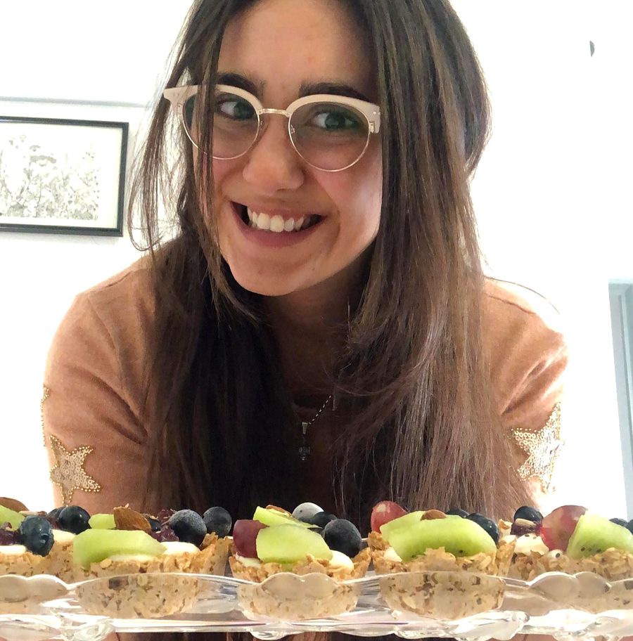 Flor sonriendo con una bandeja de tarteletas de avena con kiwi, uvas y arándanos
